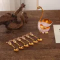 Elegant golden swan base holder with six ribbon-handle coffee spoons for home decor - Swan Base with 6 Spoons / Gold White
