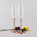 Elegante Champagnerflöten mit roségoldenen Metallstielen auf weißem Hintergrund - Farbkarton / Roségold