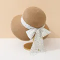 Close-up of a straw sun hat with a delicate floral bow ribbon on a display stand. - Floral Bowknot Style / Khaki
