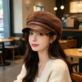 Stylish brown PU leather baker boy hat for women shown on a model in a cozy cafe - Adult 55-58cm / Suede Coffee