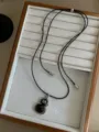 Close-up of a vintage black agate gourd pendant necklace with a leather cord strap. - Gourd Style