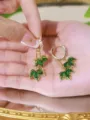 Close-up of elegant gold hoop earrings featuring green marquise stone maple leaf dangles. - Green Maple Leaf Long Huggie Earrings