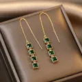 Dettaglio ravvicinato di orecchini con pietre quadrate verde smeraldo e nappa a catena oro - Stile Nappina Quadrata Smeraldo (E1709) / Oro Verde
