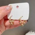 Close-up of elegant gold hoop earrings with dangling sphere charms on a display card. - Five-Bead Tassel Half-Hoop Style (E1496) / Gold