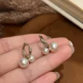 Detailed view of elegant silver hoop earrings with dual pearl accents on fingers - Bi-Color Pearl Gold