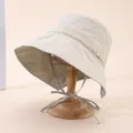 Gros plan détaillé du chapeau bob beige avec doublure à carreaux et lanières pratiques. - Adulte 55-58cm / Beige