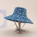 Blue floral wide brim bucket hat with adjustable strap on a wooden display stand - Adult 55-58cm / Dark Blue with White Floral (35)