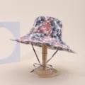 Side view detail of a wide brim floral print sun hat displayed on a wooden stand - Adult 55-58cm / Red Blue Gray Leaf Print (7)