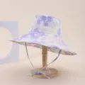 Detailed view of a purple floral sun hat with wide brim and chin strap on a stand. - Adult 55-58cm / Light Purple Floral (32)