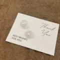 Nahaufnahme von eleganten hohlen Blumen-Perlenohrsteckern auf einer weißen Geschenkkarte. - Hohles Blütenblatt Künstliche Perle Stil (E5389) / Silber