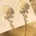 Close-up of elegant white rose earrings featuring a crystal bow and long gold tassel chains - Rose Bow Tassel Style (E3626) / Gold (E3626)
