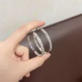 Elegant silver-toned hoop earrings with sparkling rhinestones shown held in hand - Silver (E5379)
