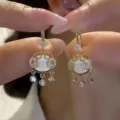 Close-up of elegant gold-tone vintage earrings with white opal and clear rhinestones. - Ruyi Lock Tassel Style (E3181) / Gold