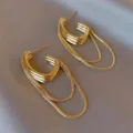 Detailed view of vintage gold C-shaped earrings with hanging snake chains on satin - Horseshoe Base Snake Bone Chain Style (E3156) / Gold