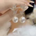Close-up detail of sparkling butterfly motifs and white pearl drop earrings - Butterfly Pearl Style (E3065) / Gold
