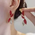 Dettaglio di eleganti orecchini a foglia rossa con strass scintillanti e finitura oro - Oro Rosso