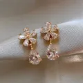 Macro view of elegant flower-shaped earrings with shimmering teardrop crystals on satin - Five-Petal Flower Drop Stud Earrings (E2498 Gold)