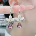 Elegant gold-tone drop earrings featuring white marquise petals and a faceted purple crystal - Purple Pear-Shaped Crystal Earrings (E2561 Purple)