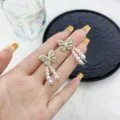 Elegant butterfly tassel earrings with pearls and crystal accents shown on the hand - Butterfly Pearl Tassel Style (E2467) / Gold