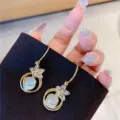 Elegant gold-tone floral dangle earrings featuring delicate white cat eye stone beads - Floral Opal White Gold (E1201)