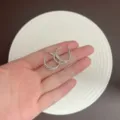 Exquisite silberfarbene strukturierte Creolen, in der Hand zur Skalierung gezeigt. - Gehämmerter Reifen Stil (E5422) / Silber Gehämmerter Reifen (E5422)