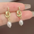 Elegant vintage style gold knotted drop earrings with white pearls held by hand. - Knot Pearl Drop Style (E3381 Gold) / Gold