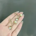Elegant gold-tone bud pearl earrings held by hand for a delicate minimalist aesthetic. - Flower Bud Double Artificial Pearl Design (E1341) / Gold