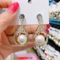 Elegant teardrop-shaped earrings with white pearls and shimmering crystal accents. - Teardrop Artificial Pearl Style (E1418) / Gold
