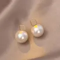 Elegant minimalist gold square stud earrings with large round white pearls on silk background - Square Base Pearl Stud Earrings (E4789) / Gold
