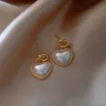 Elegant heart-shaped pearl earrings with a gold-toned knot detail and beaded edge design. - Heart Beaded Artificial Pearl Style (E1516) / Gold