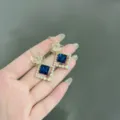 Eleganti orecchini floreali dorati con cristallo blu quadrato e accenti di perle - Stile Petalo Pietra Blu Quadrata (E1802) / Oro