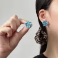 Exquisite blaue Vintage Kristall-Blumenohrringe getragen von einem Modell in Nahaufnahme. - Blaue Fünfblättrige Blume Kristall Stil (E5374) / Blau Und Silber