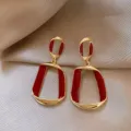 Retro geometric drop earrings with gold finish and vibrant red enamel accents. - Geometric Twist Earrings (E3212) / Burgundy