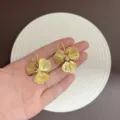 Elegante Vintage-Gold-Blumenohrringe mit funkelndem Kristall, in der Hand gezeigt - Strahlende Strukturierte Blumen-Ohrhaken (E5357) / 24K Gold