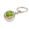 Detail view of a metal keychain with a green four-leaf clover under a glass dome. - Vintage Floral Clover (XSWX6005-2)