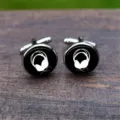 Close-up view of polished silver cufflinks with white headphone icons on black glass - Minimalist Headphones (5HXK0108-4)