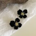 Macro view of black flocked flower earrings with gold-tone centers on textured paper - Flocked Black Four-Petal Flower Style (E2670)
