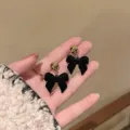 Detailed close-up showing the soft velvet texture of black bow stud earrings for winter - Flocked Black Bowknot Gold Ball Style (E3543)