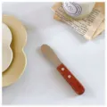 Close-up of a vintage stainless steel butter knife with a rich wood handle on a table - Beech Handle Butter Knife - Wine Red