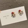 Close-up of delicate pastoral floral stud earrings with rhinestones on a card. - Floral Stud Earrings / White