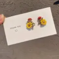 Detailed view of forest-style sunflower stud earrings with glittering rhinestones on a card - Floral Stud Earrings / Yellow