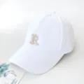 Gros plan d'une casquette de baseball blanche avec broderie beige de la lettre 'R' - Adulte 55-59cm / Blanc