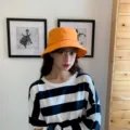 Close-up of an Asian model wearing a bright orange minimalist cotton bucket hat indoors - Adult 56-58cm / Bucket Hat Style / Orange