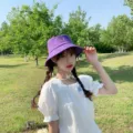 Vue lifestyle d'une femme portant un chapeau bob violet minimaliste dans un grand parc - Adulte 56-58cm / Style Chapeau Bob / Violet