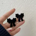 Handcrafted black flocked velvet bow stud earrings held in hand for jewelry display - Flocked Black Bowknot Style (E2689)