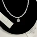 Dettaglio macro del ciondolo a bussola di lusso con zirconi e collana di perle bianche - Collana con Sfera di Strass Rotonda (R2588)