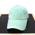 Distressed mint green baseball cap detail, featuring yellow L embroidery and brim text. - Adult 56-60cm / Green