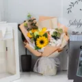 Macro view of an artificial sunflower bouquet with elegant white lace ribbon detail. - 2 Sunflowers + Cherry Blossom (With Light Bag) / Sunstone