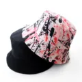 Reversible bucket hat detail shot showing stylish pink splatter print and classic black side. - Adult 55-58cm / Graffiti Pink