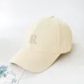 Close-up detail of a cream-colored baseball cap with an embroidered letter R logo - Adult 55-59cm / Beige